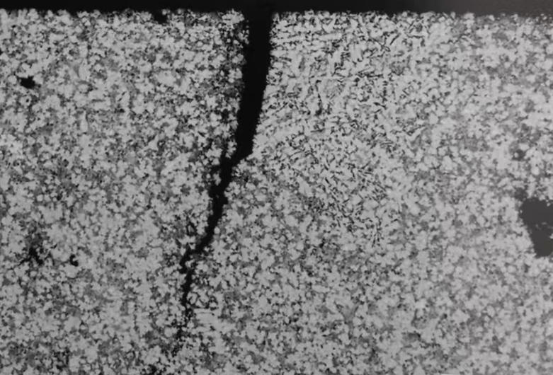 Surface-level hot tear on aluminum die-cast housing showing wavy crack lines caused by thermal stress during solidification
